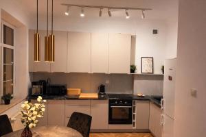 a kitchen with white cabinets and a table with chairs at PIASKI 4 - Boutique stay in Gdańsk