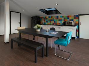 a dining room table with a blue chair and a kitchen at Ghoyhuys in Leiderdorp