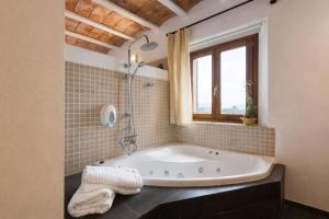 eine große Badewanne in einem Badezimmer mit Fenster in der Unterkunft Hotel Can Riera by CheelHotels in Moscari + 67 Fotos