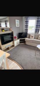 a living room with a couch and a tv at Trailer by the sea in Millom