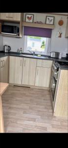 a kitchen with wooden cabinets and a counter top at Trailer by the sea in Millom