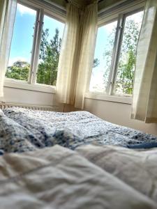 a bed in a bedroom with two windows at Cabin with beautiful view in Kolmården