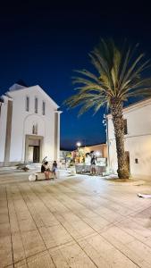 a palm tree next to a white building with two people sitting at Casa Paradiso La Cinta San Teodoro in San Teodoro
