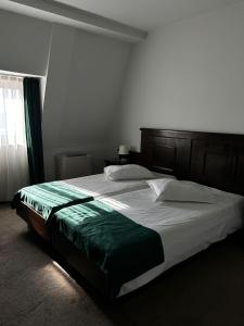 a bedroom with a large bed with a wooden headboard at Hotel Clasic in Sebeş