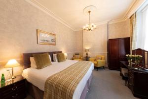 a hotel room with a large bed and a desk at Bryn Derwen with Private Car Park in Llandudno