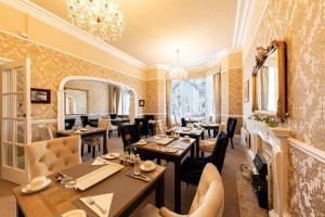 a restaurant with tables and chairs and a chandelier at Bryn Derwen with Private Car Park in Llandudno