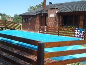 a pool with a wooden fence and a house at Complejo Rancho Grande in Nueva Atlantis