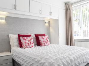 a bedroom with a large white bed with red pillows at Newcastle Lodge in Thornton