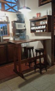 a kitchen with a wooden table with two stools at Complejo Rancho Grande in Nueva Atlantis
