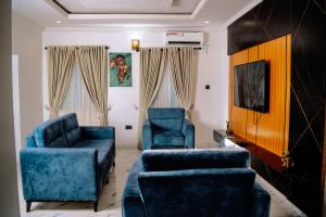 a living room with two blue chairs and a tv at Crystal Bricks Apartments in Port Harcourt