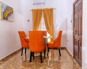 a dining room with orange chairs and a table at Crystal Bricks Apartments in Port Harcourt +3 photos