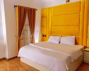 a bedroom with a large bed with a yellow headboard at Crystal Bricks Apartments in Port Harcourt