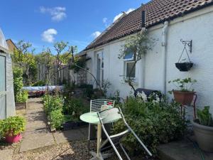 a garden with a table and a chair in front of a house at Charming Old Cottage for Share, Cosy Double Room with 2 Single Bed in Edinburgh
