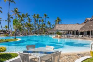 a pool with a table and chairs and palm trees at VOI Andilana Beach Resort in Nosy Be