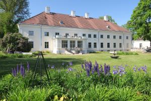 a large white house with purple flowers in the foreground at Anija mõis in Anija