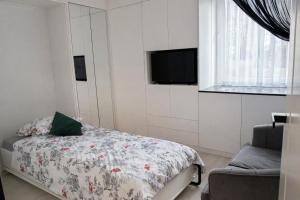 a bedroom with a bed and a tv and a window at Zielone Stablowice Wrocław in Wrocław