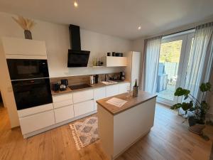 a kitchen with white cabinets and a large window at Ferienwohnung Schöne Aussicht in Löf