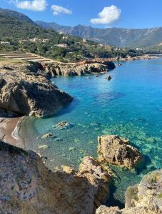 a view of a beach with blue water and rocks at Camping A Torra in Galeria