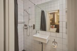 a white tiled bathroom with a sink and a mirror at Quentin Canal House Hotel in Amsterdam +68 photos