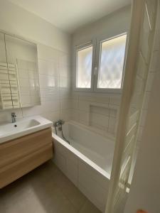 a white bathroom with a tub and a sink at Maison luxueuse proche de Paris centre in Aulnay-sous-Bois +29 photos