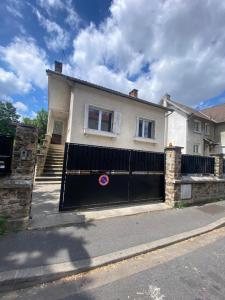 a white house with a black garage door at Maison luxueuse proche de Paris centre in Aulnay-sous-Bois
