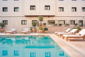 a swimming pool with lounge chairs and a building at Alora Hotel Mérida in Mérida