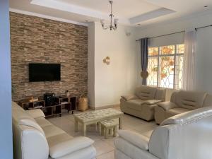a living room with white furniture and a brick wall at Inkindi House in Kigali