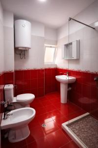 a red and white bathroom with two toilets and a sink at Dahlila's Home near Lake Ohrid in Pogradec +12 photos
