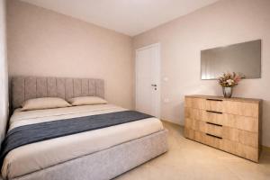 a bedroom with a bed and a dresser and a television at Dahlila's Home near Lake Ohrid in Pogradec
