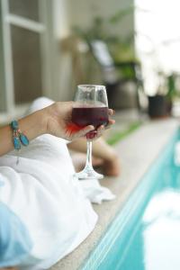 a person holding a glass of wine next to a swimming pool at The Balified Villa in Pondicherry
