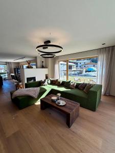 a living room with a green couch and a table at MALIA - Alpine Hideaway in Pertisau