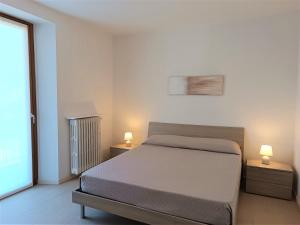 a bedroom with a bed and two lamps on two tables at Winter Spring Summer Apartments in Mergozzo