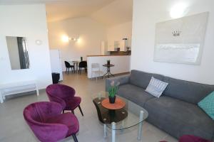 a living room with a couch and purple chairs at Apolo Apartments - Pool & Garden Retreat in Pula
