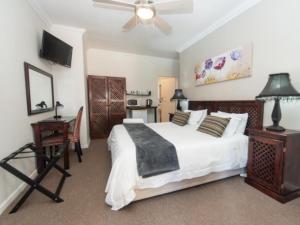a bedroom with a bed and a desk and a television at Amani Guest Lodge in Port Elizabeth