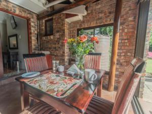 a dining room table and chairs with a vase of flowers at Amani Guest Lodge in Port Elizabeth
