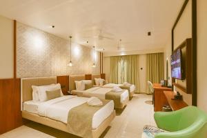 a hotel room with three beds and a flat screen tv at Len R Inn in Belgaum