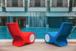two colorful chairs sitting next to a swimming pool at The Biltmore Tbilisi Hotel in Tbilisi City +110 photos