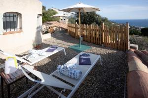a patio with two chairs and an umbrella at Meublé La Sergerie in Le Lavandou