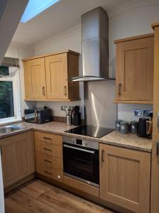 a kitchen with wooden cabinets and a stove top oven at The Cabin in Carbis Bay