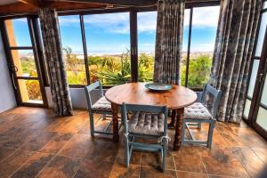 a wooden table and chairs in a room with windows at 14 Penguin Place, Melkbosstrand in Melkbosstrand