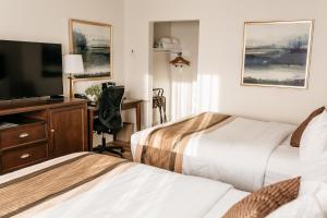 a hotel room with two beds and a desk with a television at Aurora Inn in Kingston +32 photos