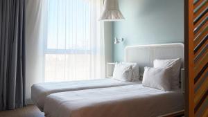 a bedroom with a bed with white pillows and a window at OKKO Hotels Nice Aéroport in Nice
