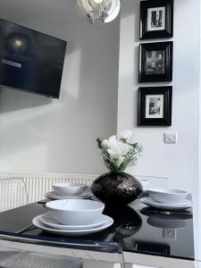 a table with white plates and a vase with flowers at New Haven Atherton Greater Manchester in Atherton
