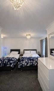 a bedroom with two beds and a mirror and a chandelier at New Haven Atherton Greater Manchester in Atherton