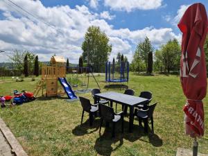 a picnic table with chairs and a playground at Cabana Apus de Soare in Râșca +26 photos