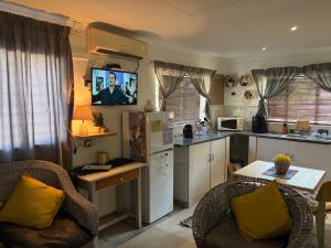 a kitchen with two chairs and a table with a tv at Evening Star Guest Units in Fichardtpark