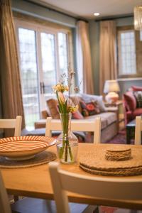 a dining room table with a vase of flowers on it at Costers Lodge in Midhurst