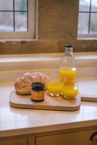 a cutting board with two glasses of orange juice and bread at Costers Lodge in Midhurst