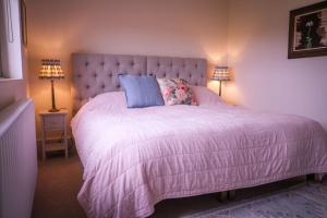 a bedroom with a large pink bed with two lamps at Costers Lodge in Midhurst
