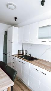 a kitchen with white cabinets and a sink and a table at Cosy apart 3 Fagaras in Făgăraş +6 photos